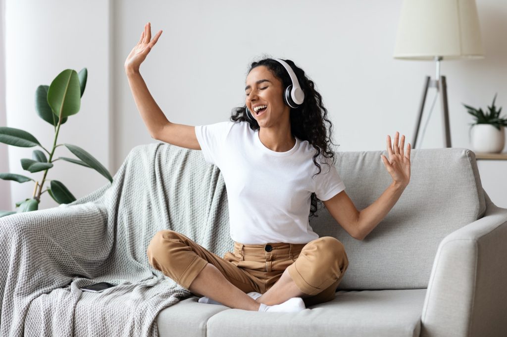 carefree woman listening to music and singing using headphones