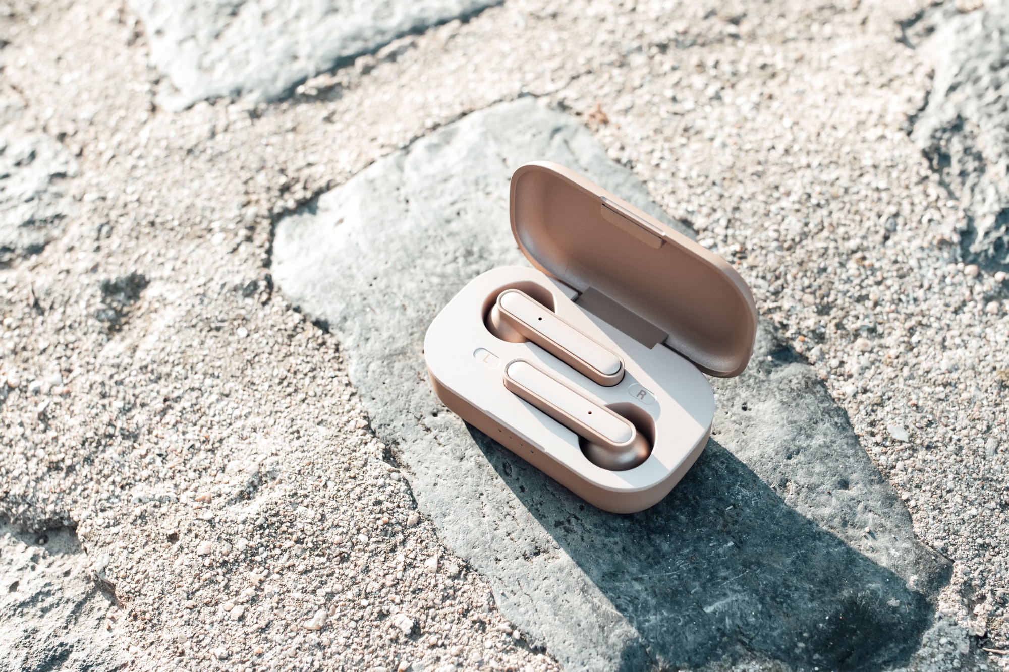 true wireless earbuds in case on natural stone background